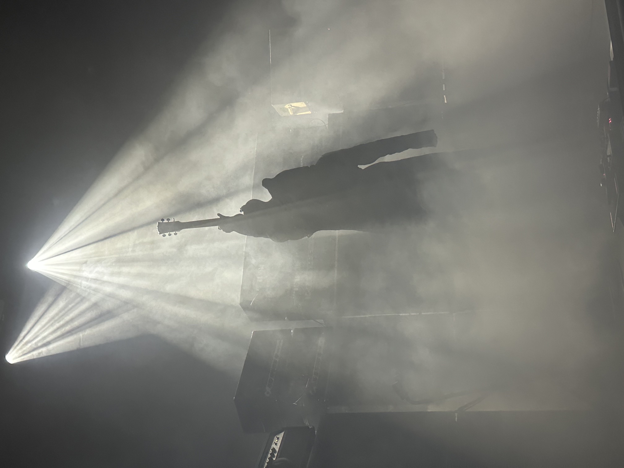 Live show, guitarist silhouetted in stage fog and light beams